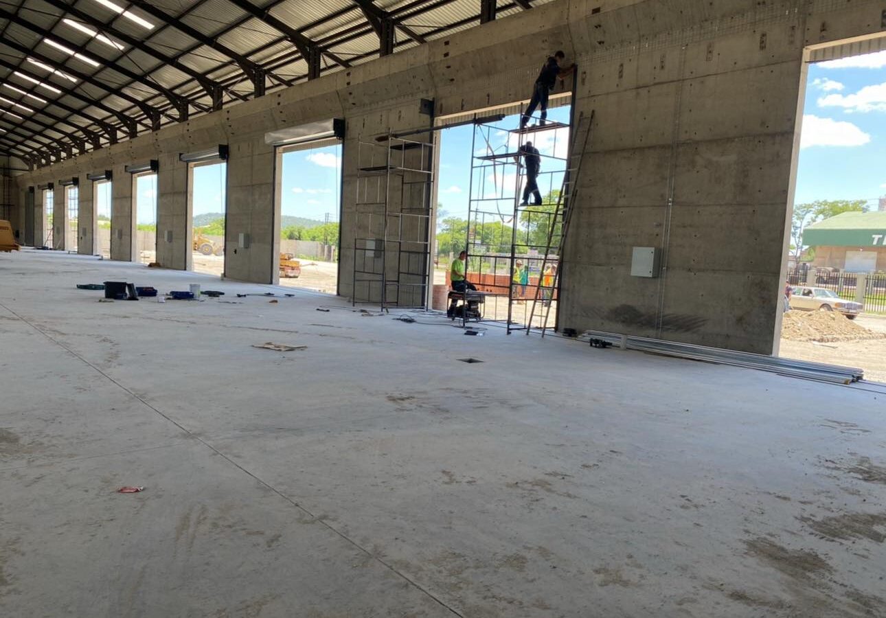 Technicians servicing roller shutter doors at height in a warehouse