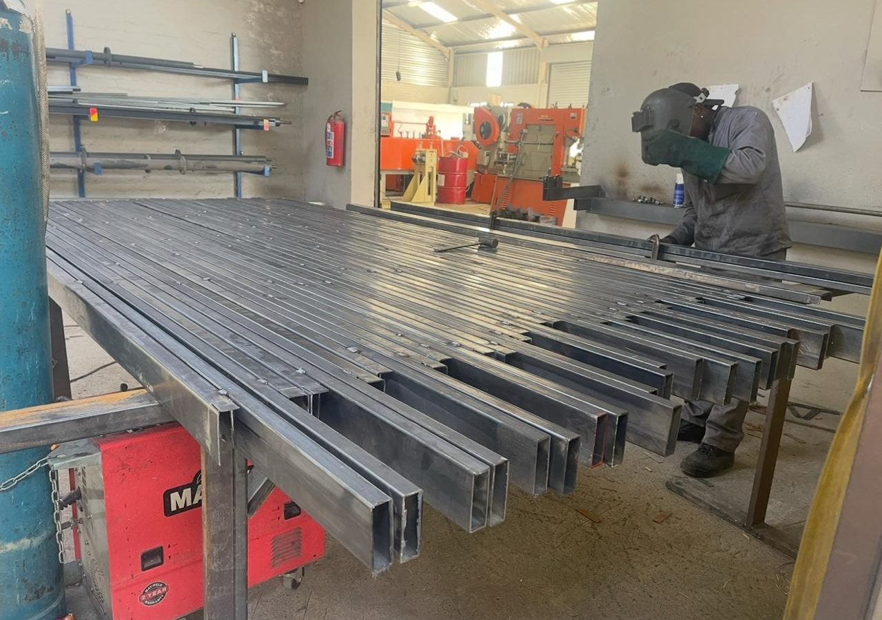 Welder fabricating roller shutter guide rails on the factory floor in Tarlton