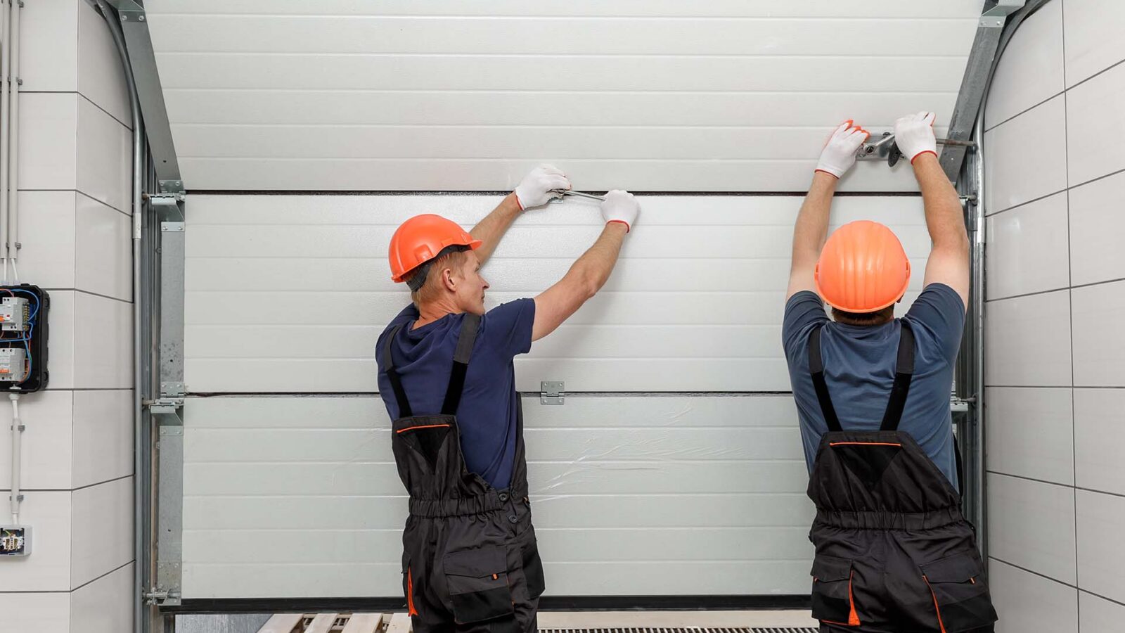 Technicians repairing a sectional garage door panel